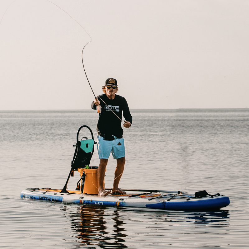 A guy fishing on a HD Aero 11′6″ Fischer Topwater Inflatable Paddle Board