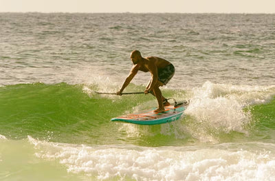 Man riding a wave near shore on the Breeze Gatorshell.