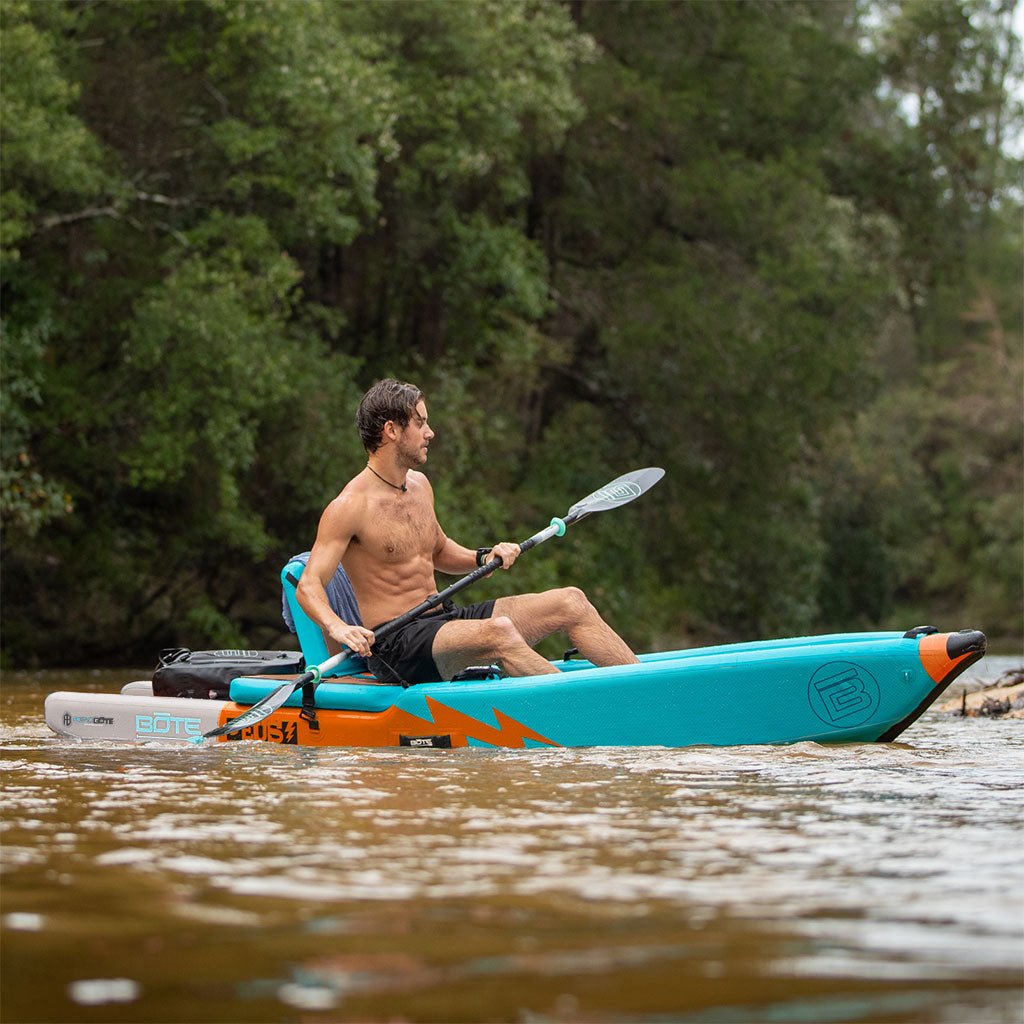 Man paddling on a blue and orange kayak on a river