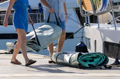 Two people carrying a rolled-up Hangout Docks to their boat in the Marina.