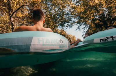 Over-under water view of people floating downstream on mint-colored FLOATubes.