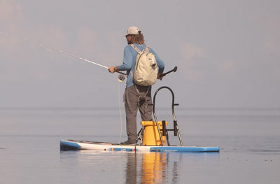 Man fishing from an HD Gatorshell paddle board equipped with gear and a KULA yellow cooler.