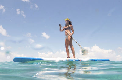 Woman paddling on an HD Gatorshell board wearing a snorkel mask in clear ocean water.