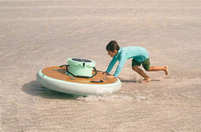 Child pushing the KULA Bar through shallow water on a beach.