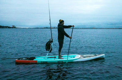 Woman standing and paddling on the Rackham GS in calm water.