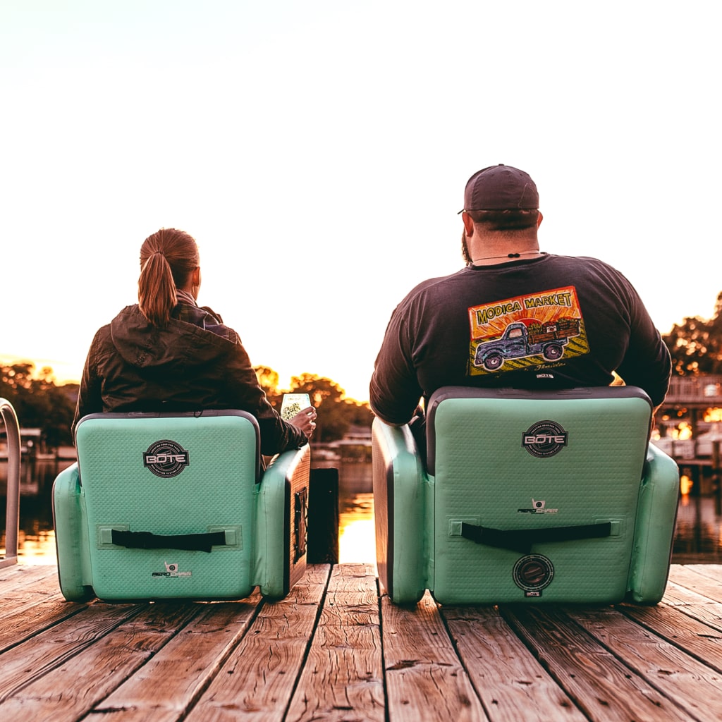 Man and woman sitting on their dock in their Aero Chairs, woman sitting in the Aero chair and man sitting in the Aero Chair XL