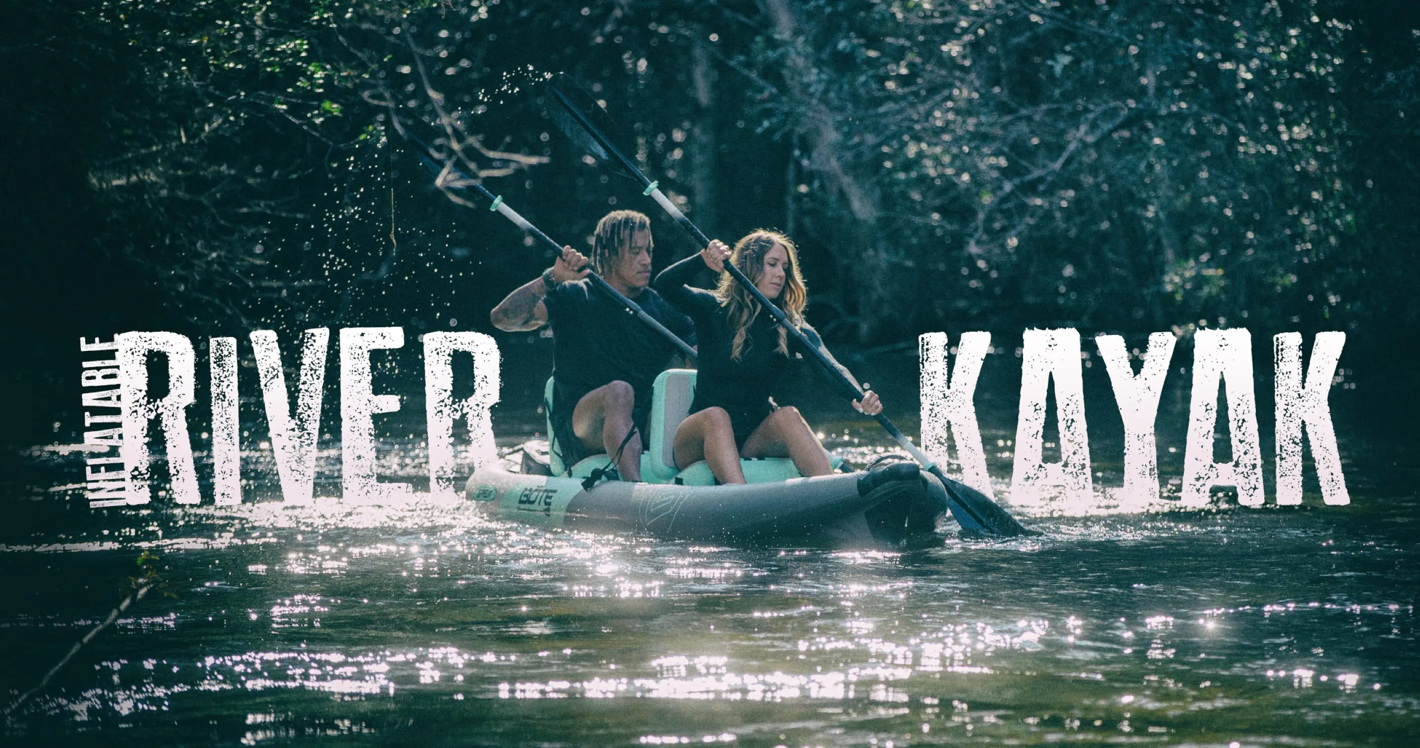 Two people on a river, kayakying together on a bright blue BOTE Kayak.