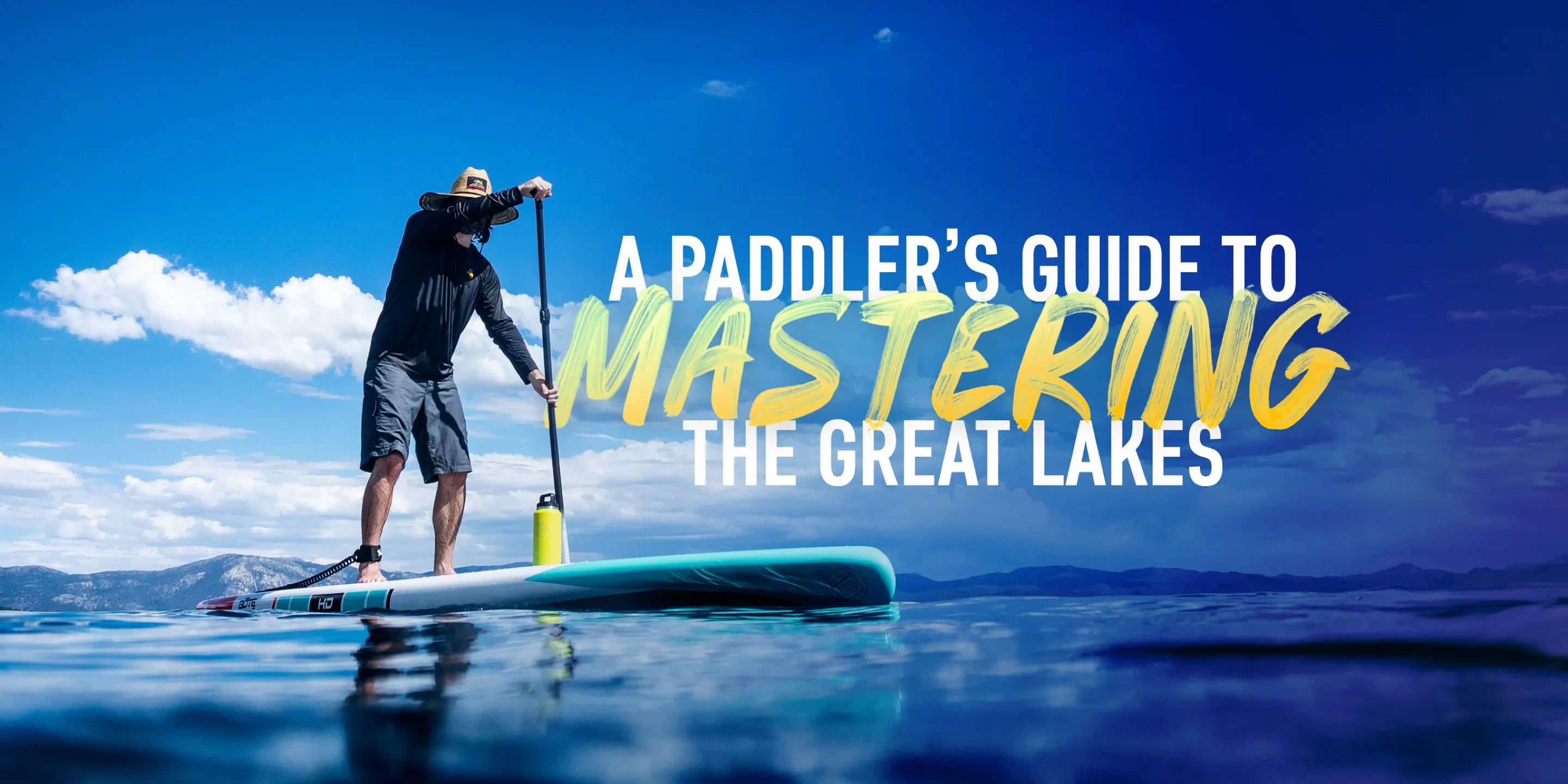 A paddle boarder on calm blue water wearing a black shirt and blue shorts with text overlay saying "A paddler's guide to mastering the Great Lakes"