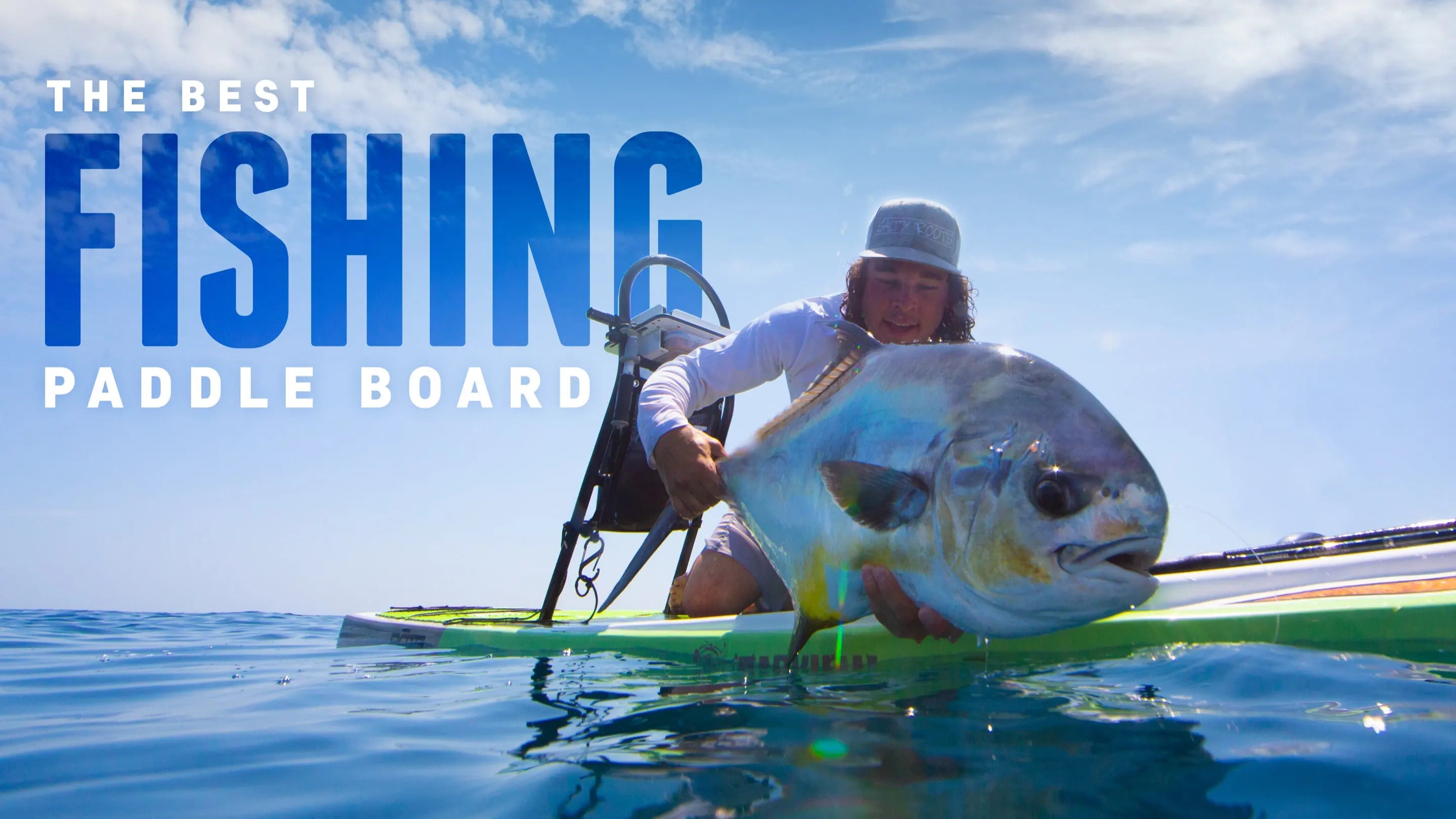 Paddle boarder holding up a massive fish that he caught on his paddle board leaning towards the camera with words that say "The best fishing paddle board"