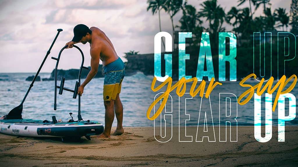 Man attaching a gear rack to a paddle board on the beach.
