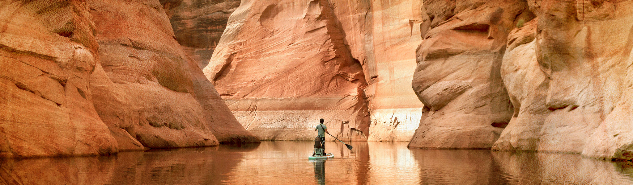 Person standing in a narrow canyon with water on either side
