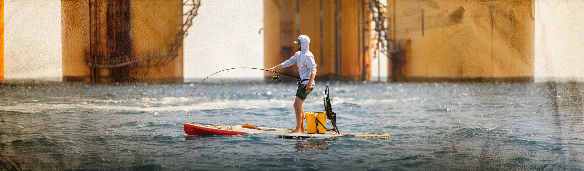 Person paddleboarding with a dog on a yellow raft near a dam.
