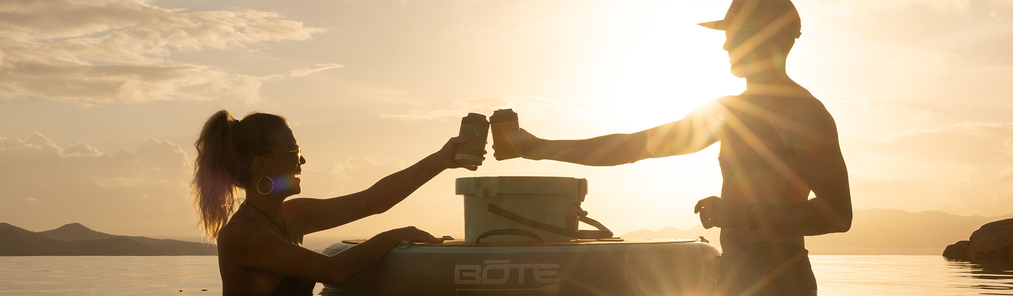 Two people holding drinkware while standing in waist deep water