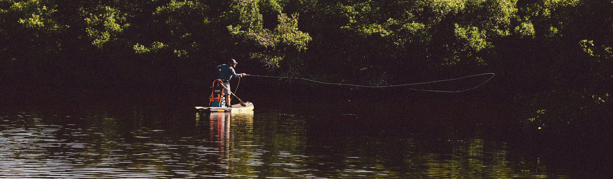 A guy fly fishing on a Rackham Aero inflatable paddle board