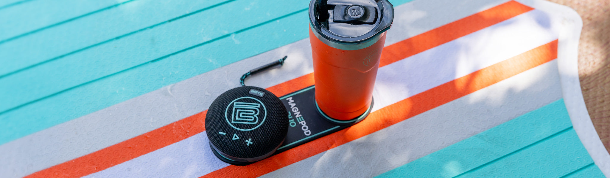 Orange tumbler with a black lid on a paddle board