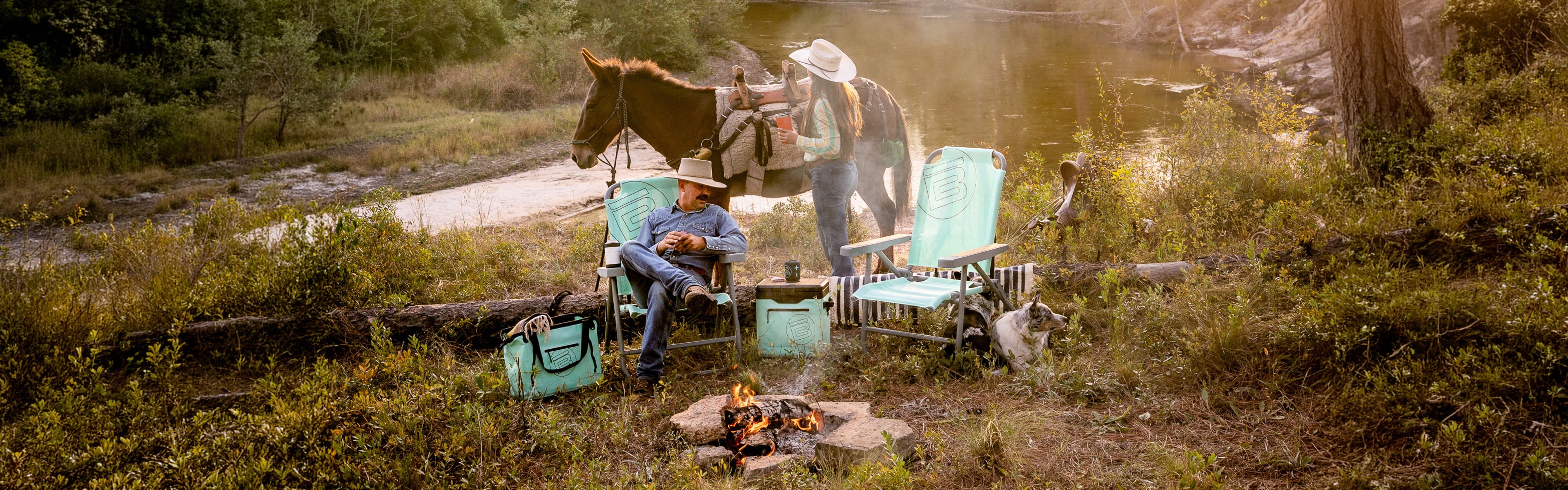 Two people with a horse and two chairs by a campfire in a forest setting.