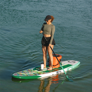 Woman paddleboarding on a Breeze Gatorshell with a cooler and tumbler on calm water.