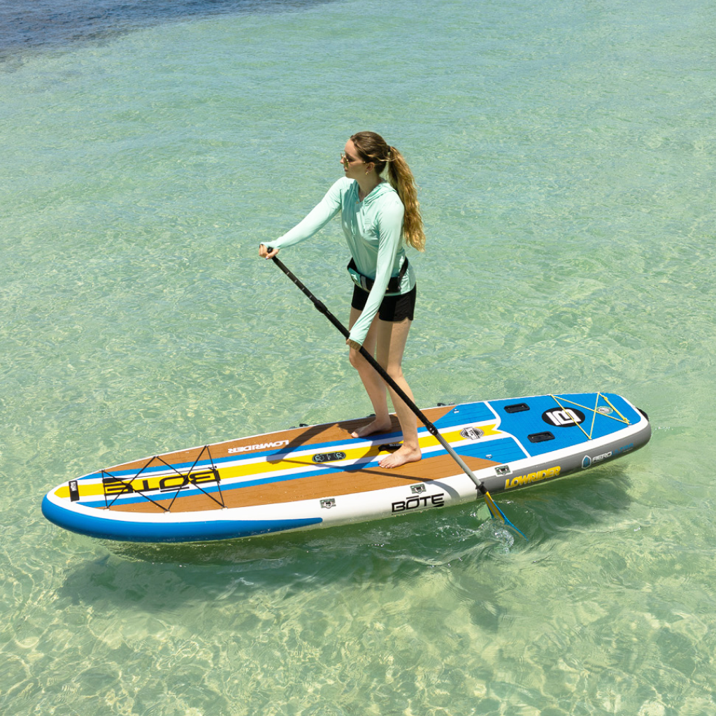 Woman stand-up paddleboarding on a LowRider Aero in clear shallow water.