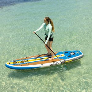 Woman stand-up paddleboarding on a LowRider Aero in clear shallow water.