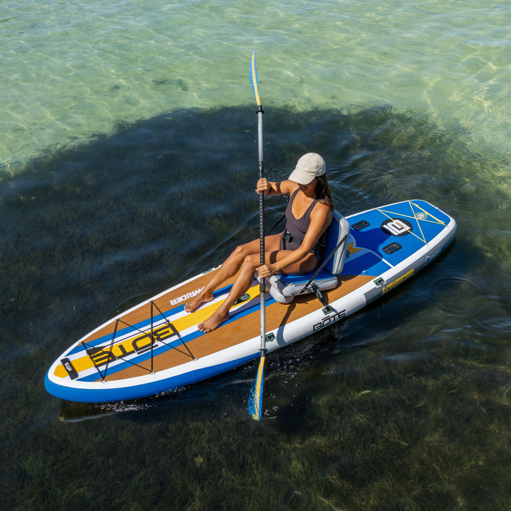 Woman seated kayaking on a LowRider Aero inflatable SUP on open water.