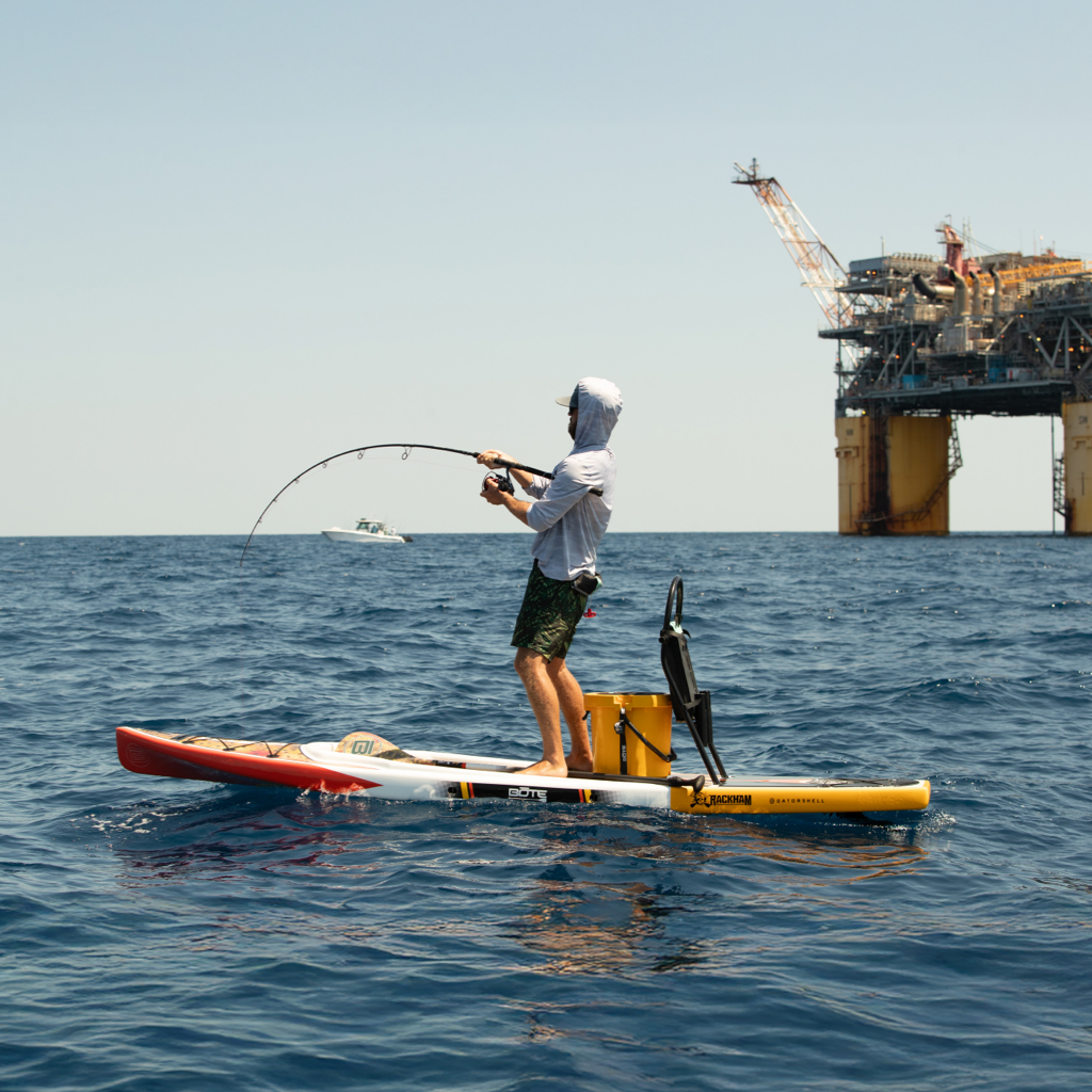 Man fishing on a paddle board in the ocean.