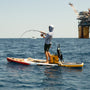 Man fishing on a paddle board in the ocean.