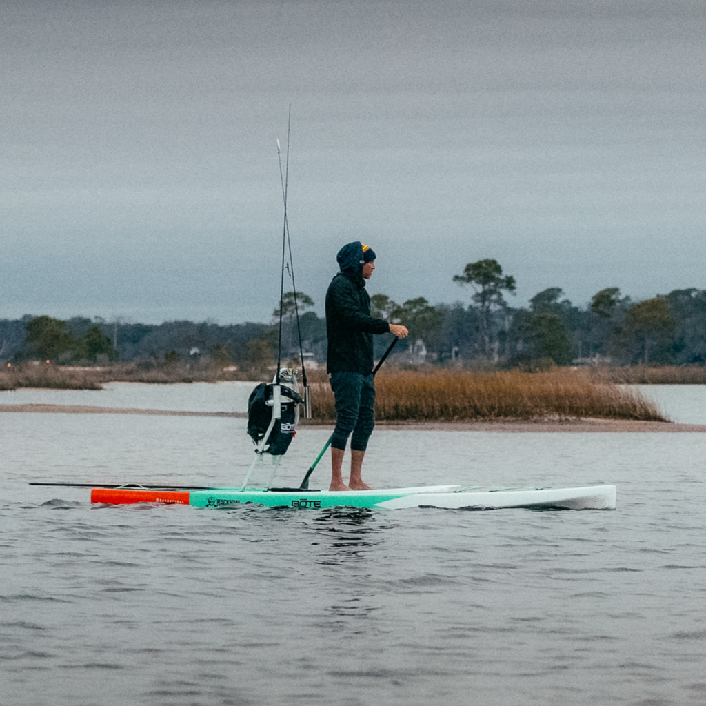 A guy paddling on the water on a Rackham 14′ Classic Mangrove Paddle Board