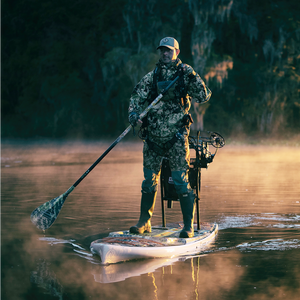 Person on a stand-up paddleboard with camouflage gear on a misty lake