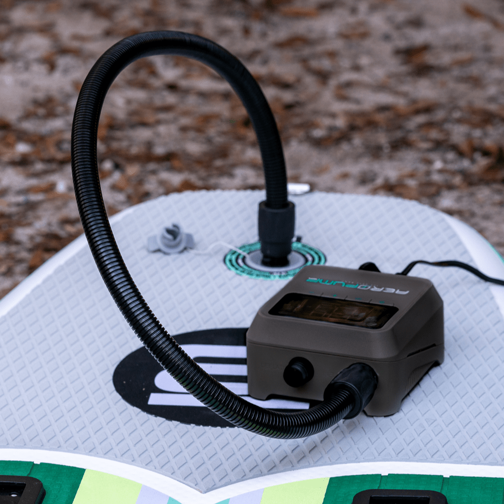 AeroPump Mini 12 Volt Pump inflating paddle board on grass.