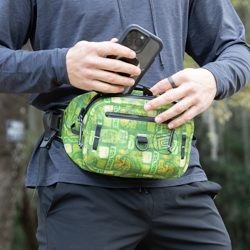 A person placing a phone in the Highwater Belt Pack Native Nalu