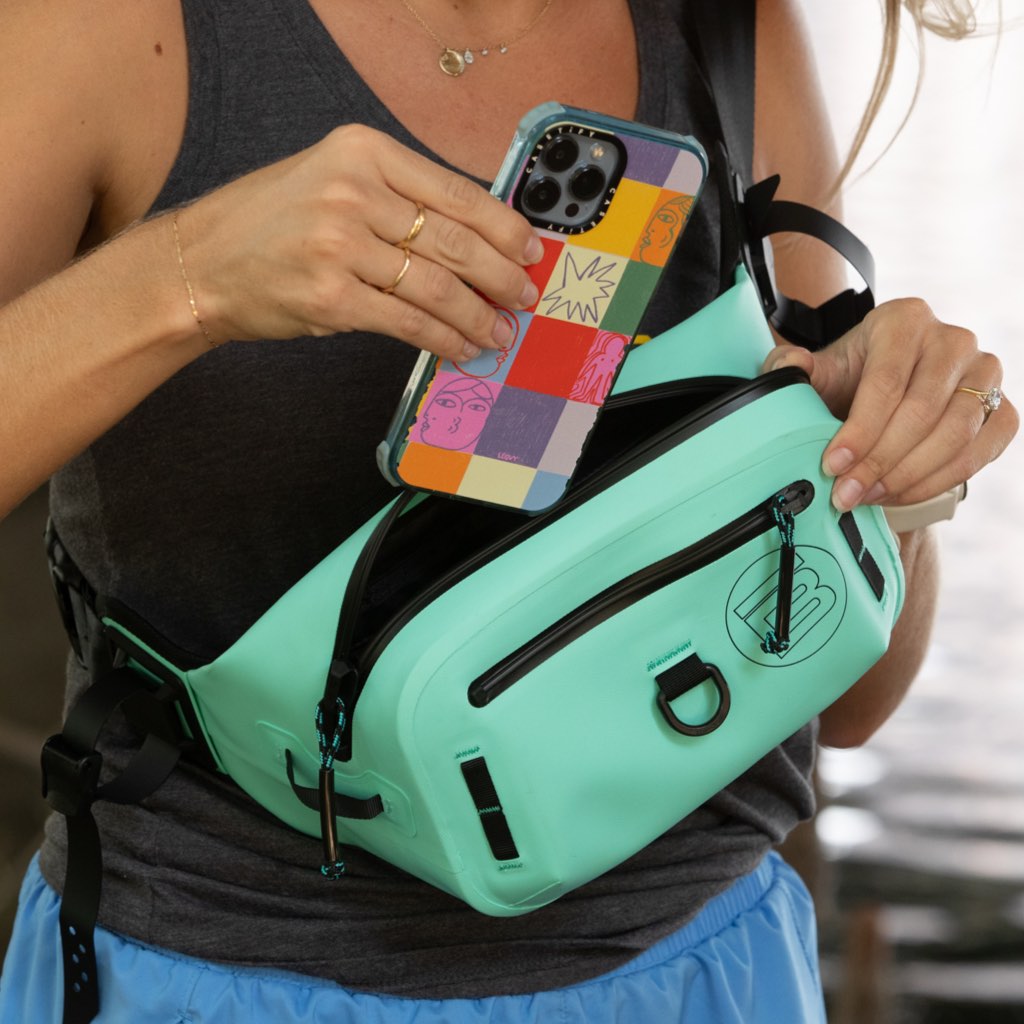 Highwater Belt Pack Seafoam worn at the waist, phone being placed in front zip pocket.