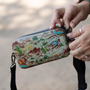 Close-up of hands unzipping Highwater Hitchhiker Native Sendero with desert scene print.