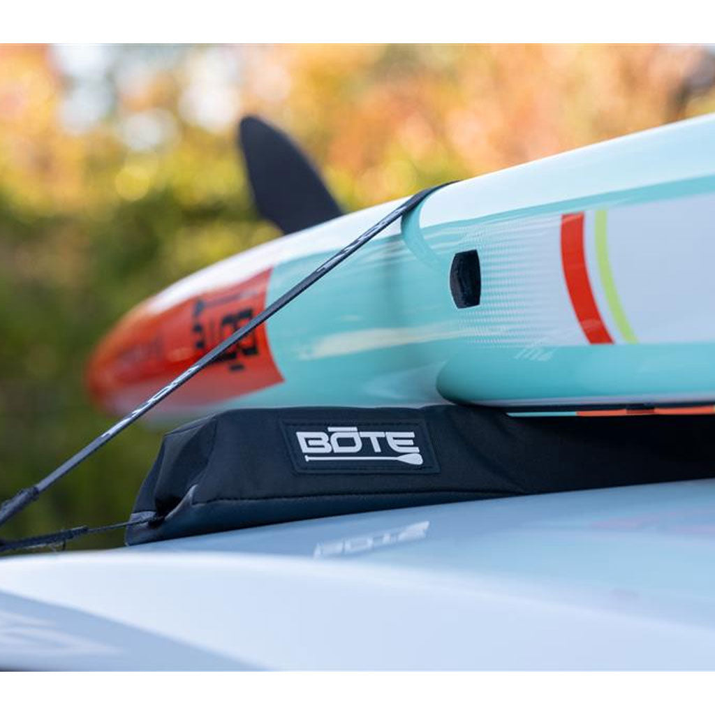 Close-up of a BOTE paddleboard  strapped to a padded BOTE roof rack with a blurred natural background