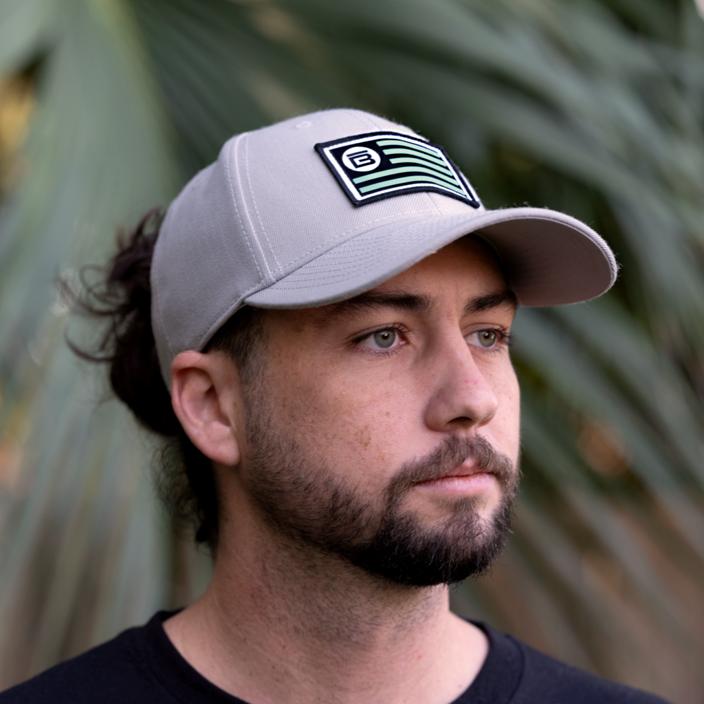 Person wearing BOTE Nation Flag Hat Gray in Grey with seafoam green, white and black patch.