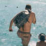 Man with a backpack jumping into the water
