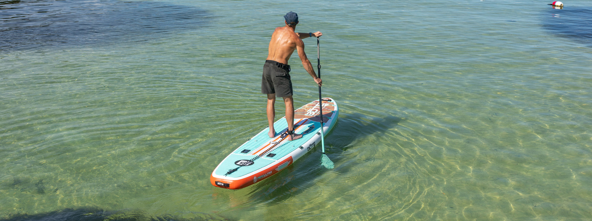 Man paddleboarding on a clear, calm body of water