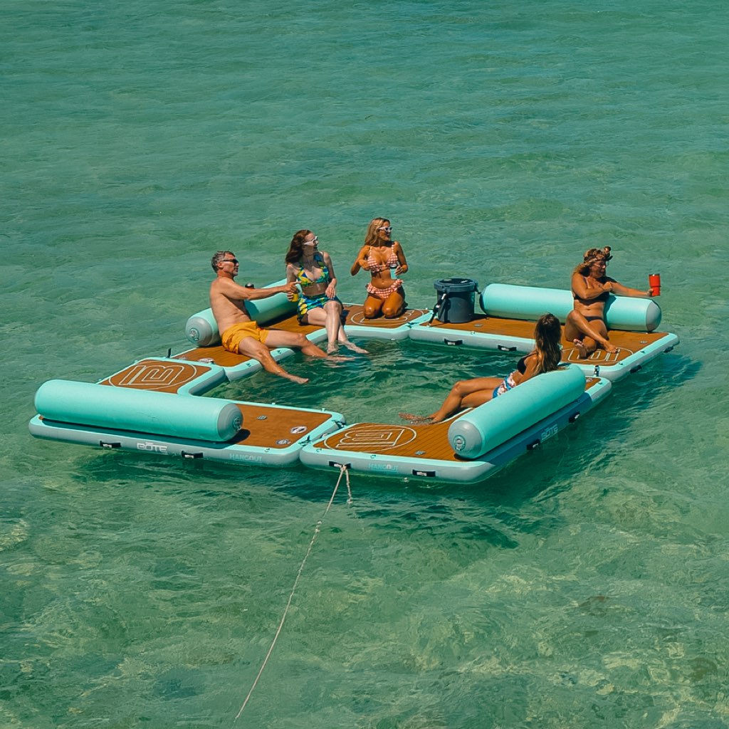 People lounging on the Inflatable Dock Hangout Quad Square [Port] on the water