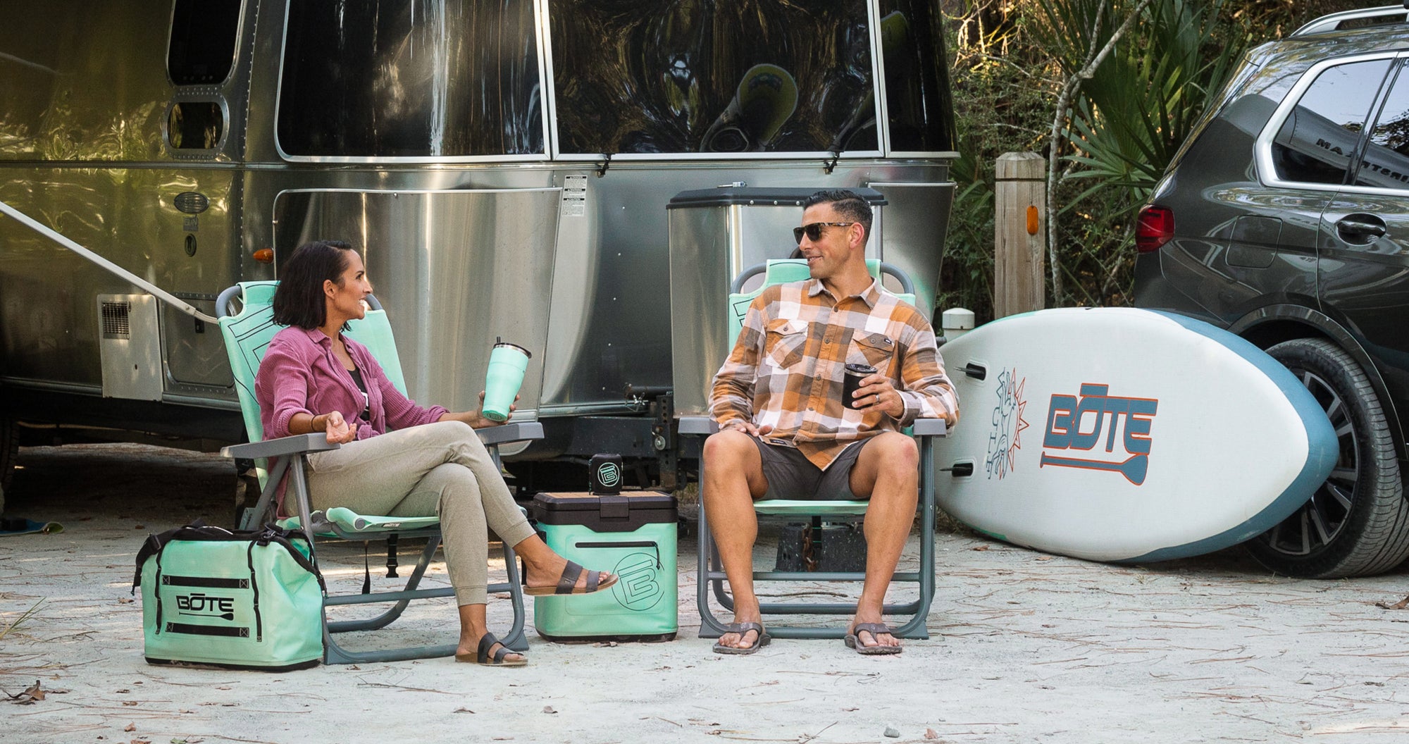 Mule Outpost Chair set with cooler and gear beside camper trailer outdoors.