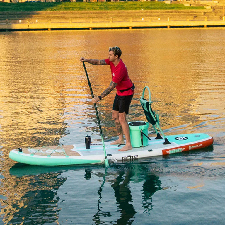 Man paddleboarding on a calm body of water with a scenic background