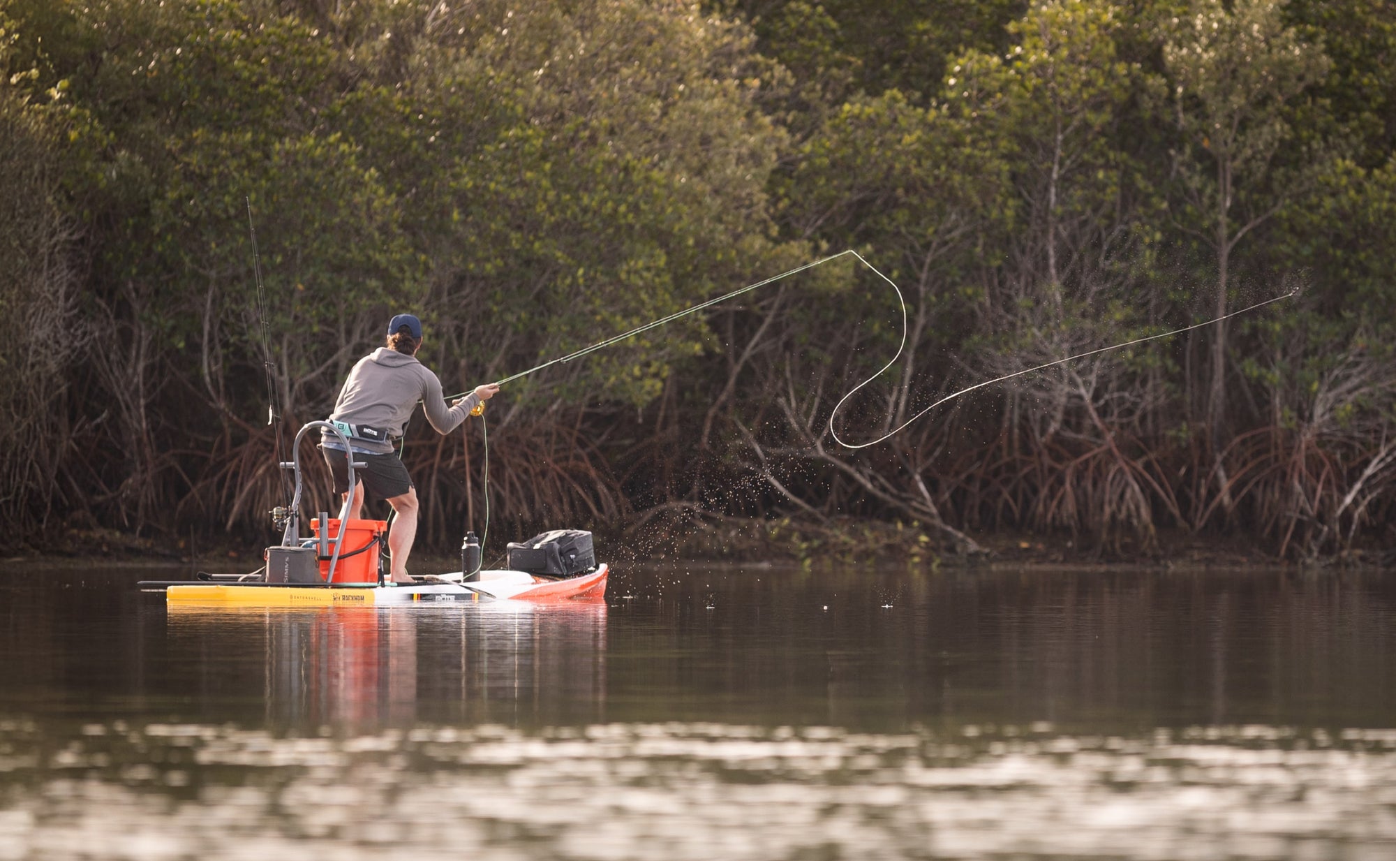 Angler fly-fishing from a Rackham Gatorshell paddle board near mangroves.