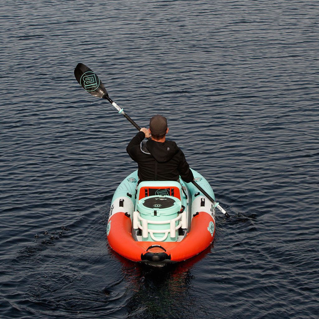 Person paddling a small inflatable kayak on calm water