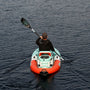 Person paddling a small inflatable kayak on calm water