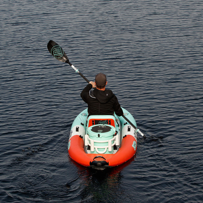 Person paddling a small inflatable kayak on calm water