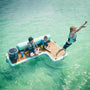 A kid jumping off the Inflatable Dock Hangout Couch [Starboard] Classic into the water