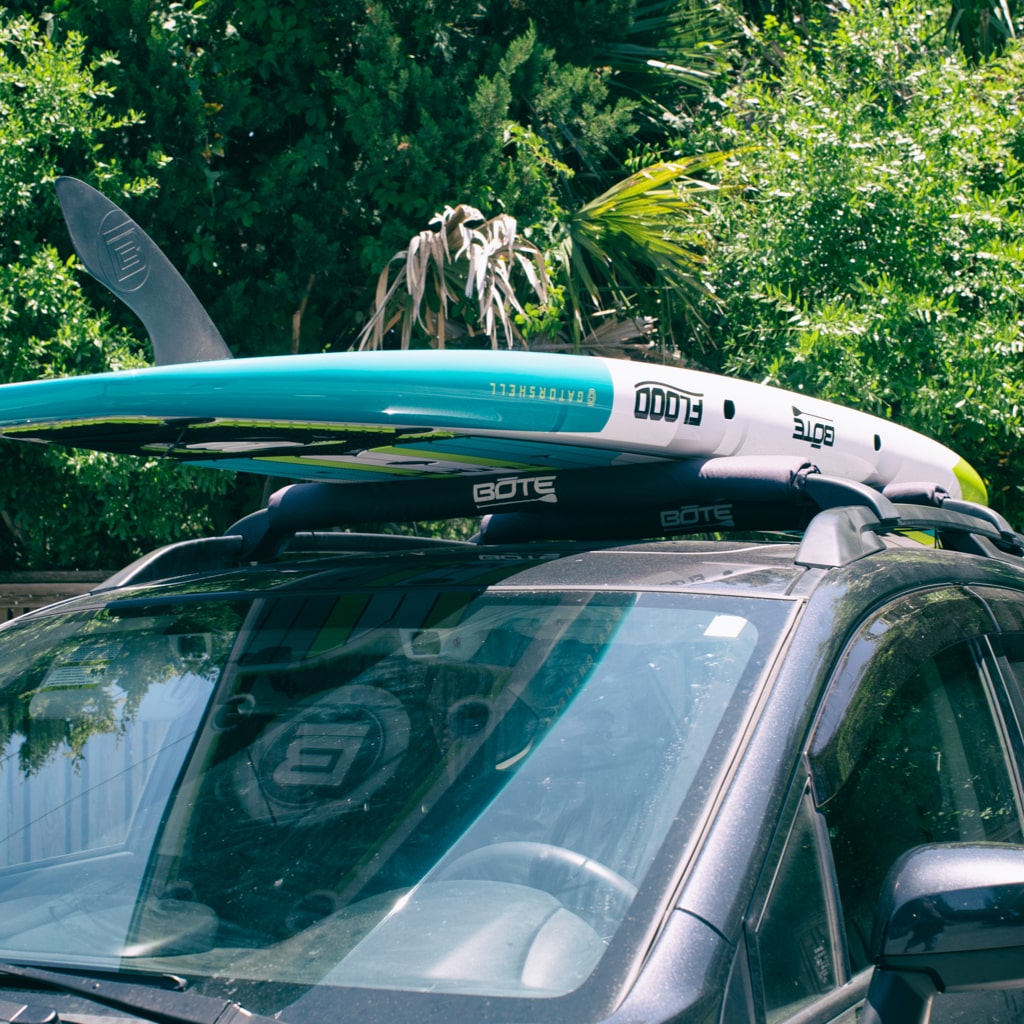 Paddle board on top of a SUV with roof racks and roof rack pads