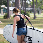 woman carrying her paddle board in a board bag using the shoulder strap