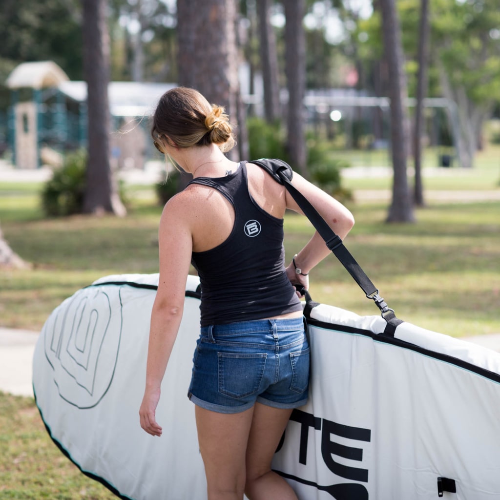 woman carrying her paddle board in a board bag using the shoulder strap