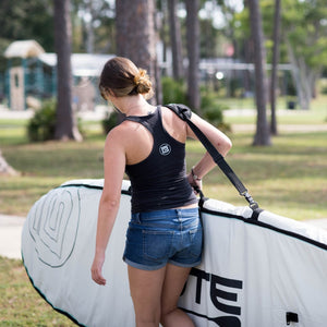woman carrying her paddle board in a board bag using the shoulder strap