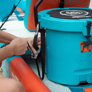 Woman using the cooler tie-down straps to secure a KULA 5 cooler to a DEUS Aero inflatable kayak