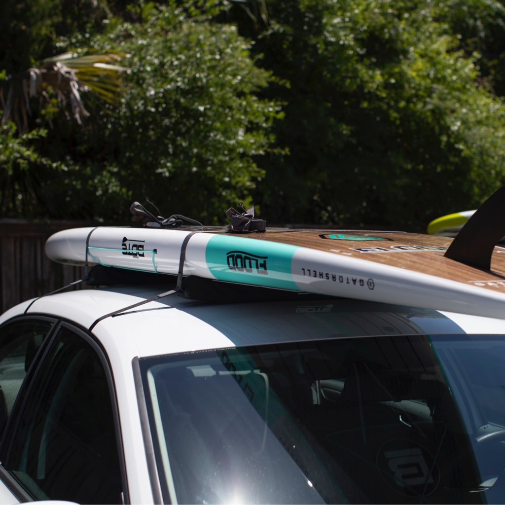 Paddle Board strapped to the top of a Quick Strap Board Rack on top of a sedan